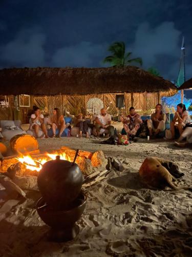 a group of people sitting around a fire on the beach at Namaste Beach Club & Hotel in Tierra Bomba
