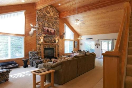 a living room with a large couch and a stone fireplace at Spacious cabin with game room free WIFI & parking in Shaver Lake