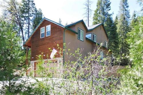 a house in the middle of a forest at Spacious cabin with game room free WIFI & parking in Shaver Lake