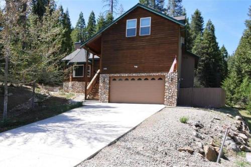 a house with a garage and a driveway at Spacious cabin with game room free WIFI & parking in Shaver Lake