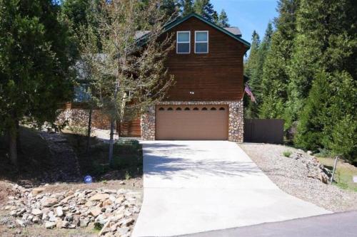 a house with a garage with a driveway at Spacious cabin with game room free WIFI & parking in Shaver Lake
