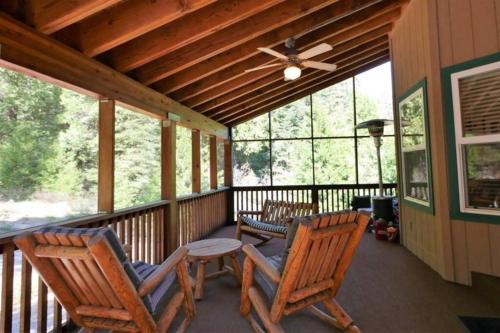 a screened in porch with two chairs and a ceiling fan at Spacious cabin with game room free WIFI & parking in Shaver Lake