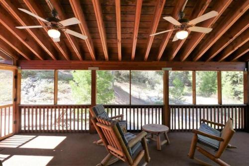 a screened in porch with two chairs and a table at Spacious cabin with game room free WIFI & parking in Shaver Lake