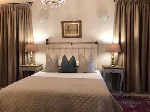 a bedroom with a bed with three pillows on it at Gooding's Olive Villa in Franschhoek