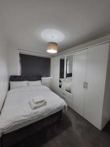 1 dormitorio con 1 cama blanca y armario blanco en Serene 3BR home with free parking en Mánchester