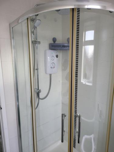 a shower with a glass door in a bathroom at Serene 3BR home with free parking in Manchester