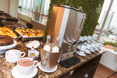 a counter with a mixer and cups of coffee and pastries at Floresta Hotel - Expo C Norte - Distrito Anhembi in Sao Paulo