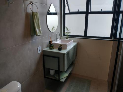 bagno con lavandino e specchio di Flat São Vicente 5 minutos da praia a São Vicente