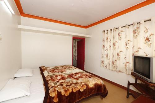 a bedroom with a bed and a flat screen tv at Hotel Sri Balaji in Ooty