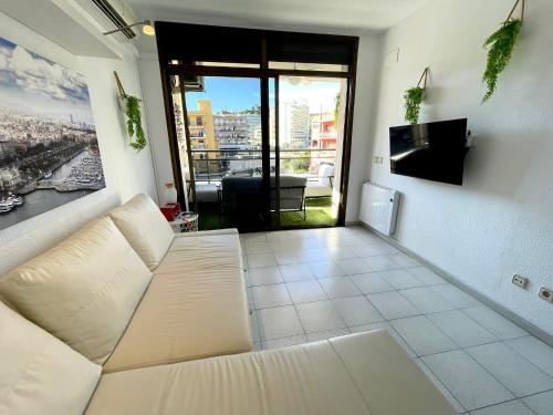 ein Wohnzimmer mit einem weißen Sofa und einem großen Fenster in der Unterkunft Apartemento piscina centro calella 3 min playa in Calella