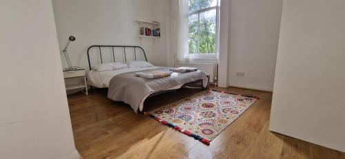 a bedroom with a bed and a rug and a window at Primrose Hill - Charming, Cosy, 2 Double Bedrooms Apartment in London