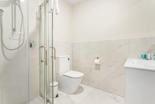 a white bathroom with a toilet and a shower at Urban Glow Townhouse with parking in Auckland