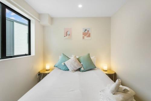 1 dormitorio con 1 cama blanca grande y 2 lámparas en Urban Glow Townhouse with parking, en Auckland
