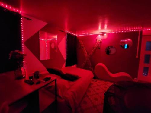 Habitación roja con sofá y cama con luces en Studio cosy entre amoureux, en Verneuil d'Avre et d'Iton