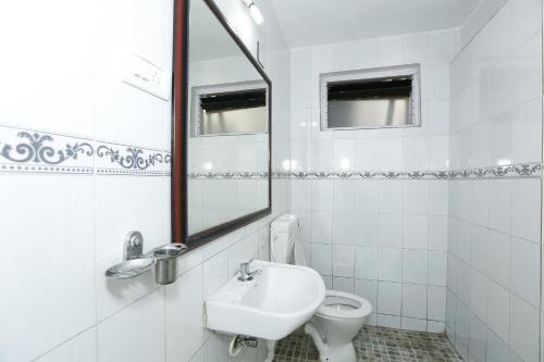 a white bathroom with a sink and a mirror at Hotel Sri Balaji in Ooty