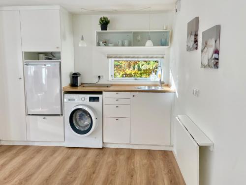 a kitchen with a washer and dryer in it at Cozy private annex near bathing lake and 30 min. from Copenhagen in Slangerup