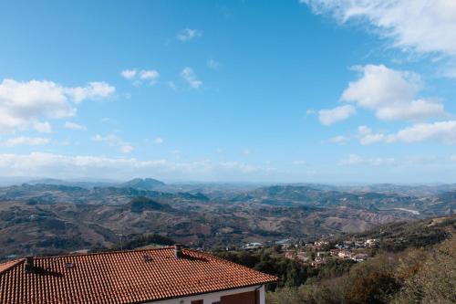 Blick auf ein Tal mit einem Haus und Bergen in der Unterkunft Above The Sky - Flying Apartment in San Marino