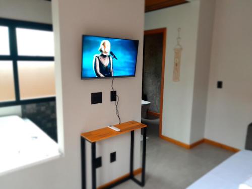 um quarto com uma televisão de ecrã plano na parede em Pousada Kirana na Praia do Rosa