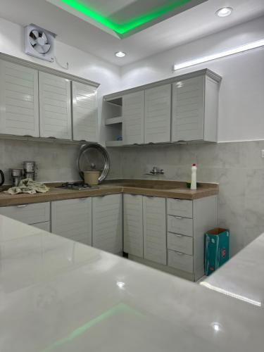 a kitchen with white cabinets and a green ceiling at استراحة سعد للايجار اليومي in Jubbah