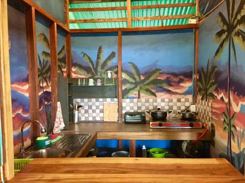 una cocina con palmeras pintadas en la pared en Oasis Beachfront Hostel, en Puerto Limón