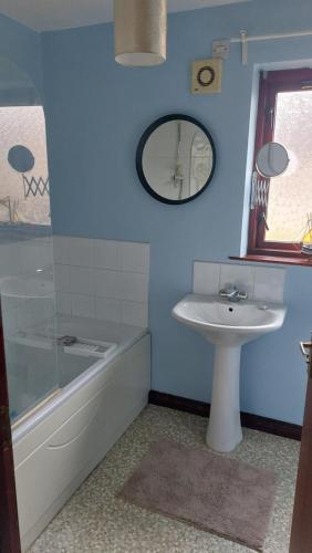 a bathroom with a sink and a tub and a mirror at The Nest Antrim in Antrim