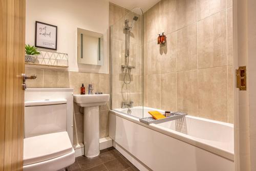 a bathroom with a tub and a toilet and a sink at 2 Bed Chic City Apartment, Spacious, Sleeps 6, with onsite Parking- Near Gunwharf Quays & Beach - By Blue Puffin Stays in Portsmouth