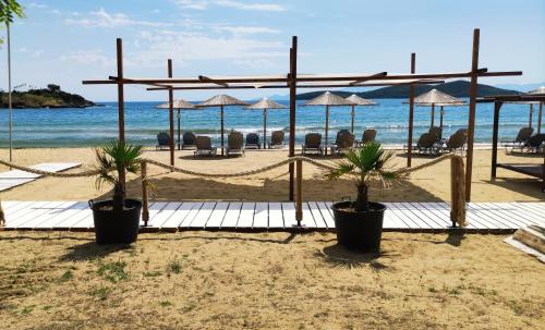 una spiaggia con sedie e ombrelloni e l'oceano di Sea View Apartments Nikos a Néa Péramos