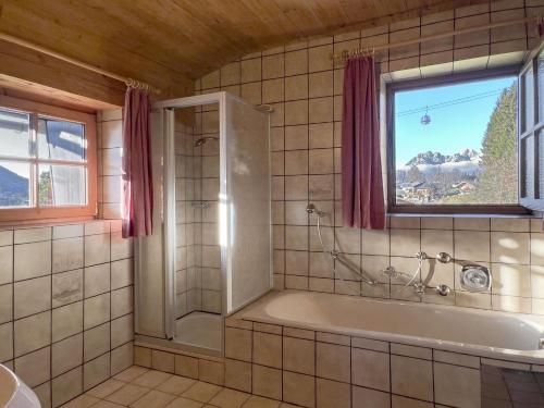 a bathroom with a tub and a window at Chalet Horn by Apartment Managers in Kitzbühel