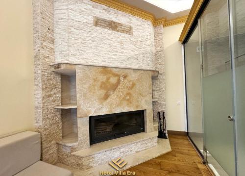 a stone fireplace in a room with a glass door at Hotel ERA in Pristina
