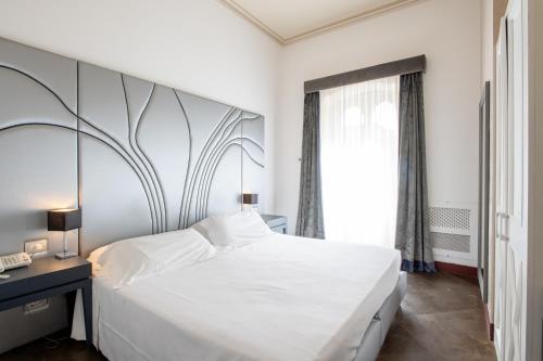 a bedroom with a large white bed and a window at De Stefano Palace Luxury Hotel in Ragusa