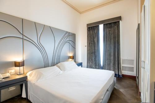 a bedroom with a large white bed and a window at De Stefano Palace Luxury Hotel in Ragusa