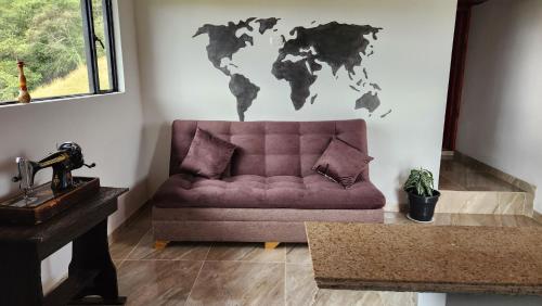 a purple couch in a living room with a world map on the wall at Carpe Diem in Guatavita
