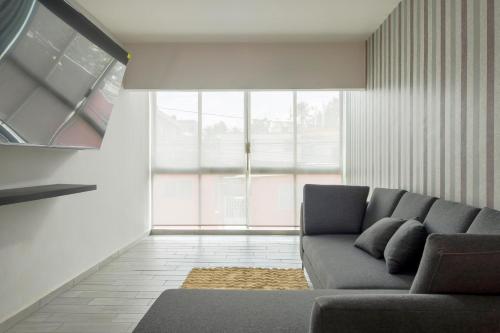 a living room with a couch and a large window at Departamento Punta Rio Cerca del Mar in Veracruz