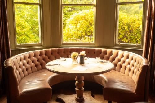 a booth with a table in a room with windows at Craigellachie Hotel of Speyside in Craigellachie