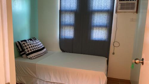 a bed in a room with a window with a pillow on it at Duran Pool & Guesthouse in Sison
