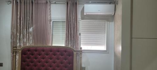 a room with a window and a red chair in front at Oscar in Ariana