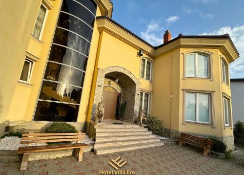 a yellow building with a large window and a bench at Hotel ERA in Pristina