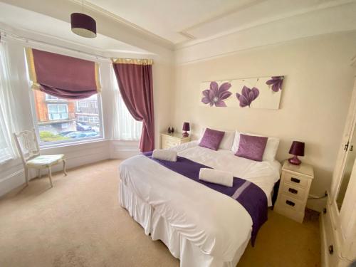 a bedroom with a large white bed with purple pillows at Stoke villas in Gosport