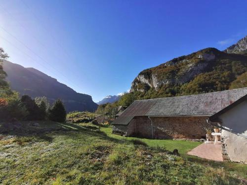 une grange dans un champ avec des montagnes en arrière-plan dans l'établissement Lou cridadé, à Laruns