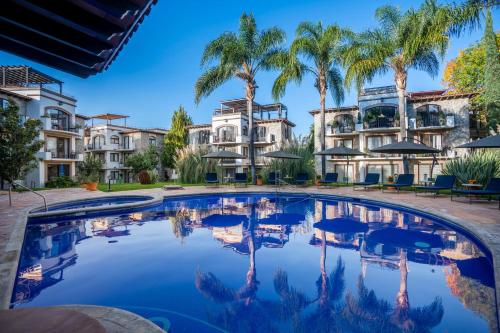 a large swimming pool with palm trees and buildings at Gated Community Home, Parking, Pool, Tennis court in San Miguel de Allende