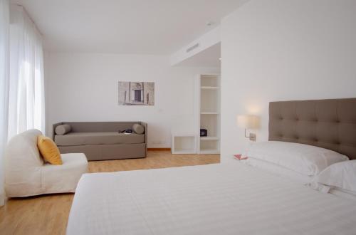 a white bedroom with a large bed and a couch at Mistral2 Hotel in Oristano