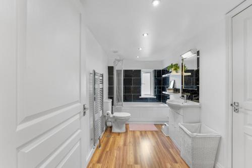 a white bathroom with a tub and a toilet and a sink at Sea La Vie - central home w BBQ, Sunny Patio, Luxurious interiors and seconds from Beach in Kent