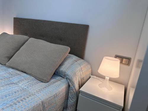 a bed with a pillow and a lamp on a night stand at Apartamento Gran Vía - PARKING GRATIS in Salamanca