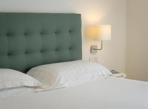 un lit avec une tête de lit bleue et une table avec une lampe dans l'établissement Mistral2 Hotel, à Oristano