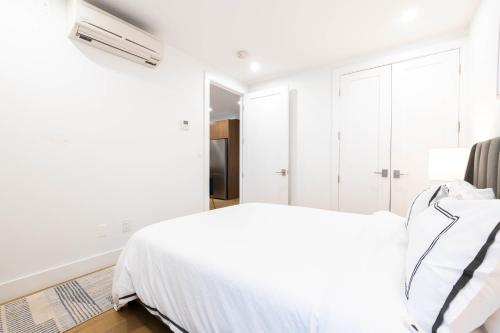 a white bedroom with a bed and a closet at 149BK-202 NEW Condo 1BR IN PRIME GREENPOINT BK in Brooklyn