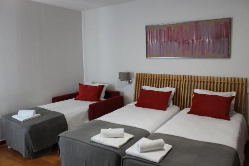 two beds in a room with red pillows on them at Hotel Paulo VI in Rio Maior