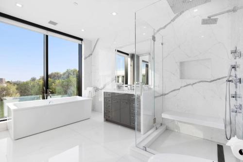 a white bathroom with a tub and a sink and a shower at Exquisite Hamptons Mansion Retreat in Water Mill