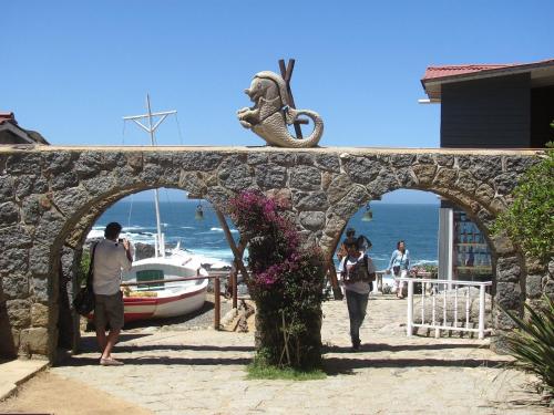 a group of people walking under a stone bridge near the beach at Casas Isla Negra in El Quisco