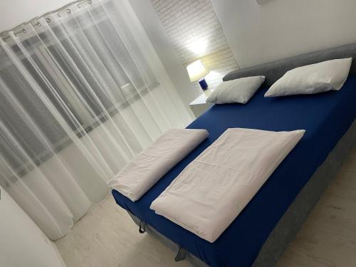 Una cama azul con almohadas blancas en una habitación en Ivan en Široki Brijeg