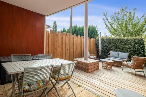 une terrasse en bois avec une table et des chaises. dans l'établissement Appartement Exupéry - Welkeys, à La Teste-de-Buch